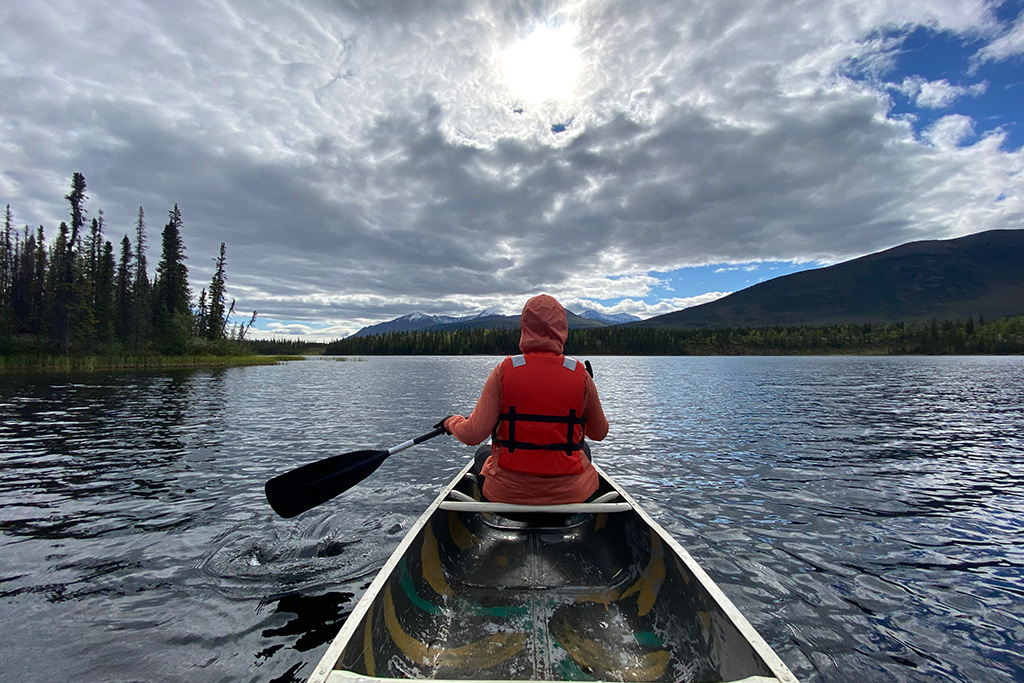 Must-pack for summer in Alaska - warm hoodie perfect for kayaking adventures - in this picture, Agnes paddles in Gates of the Arctic National Park.