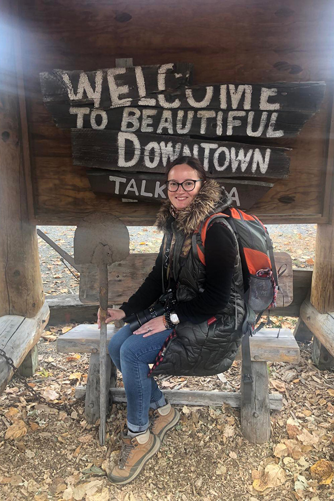 Agnes Stabinska, the author, with the sign welcome to beautiful downtown Talkeetna.