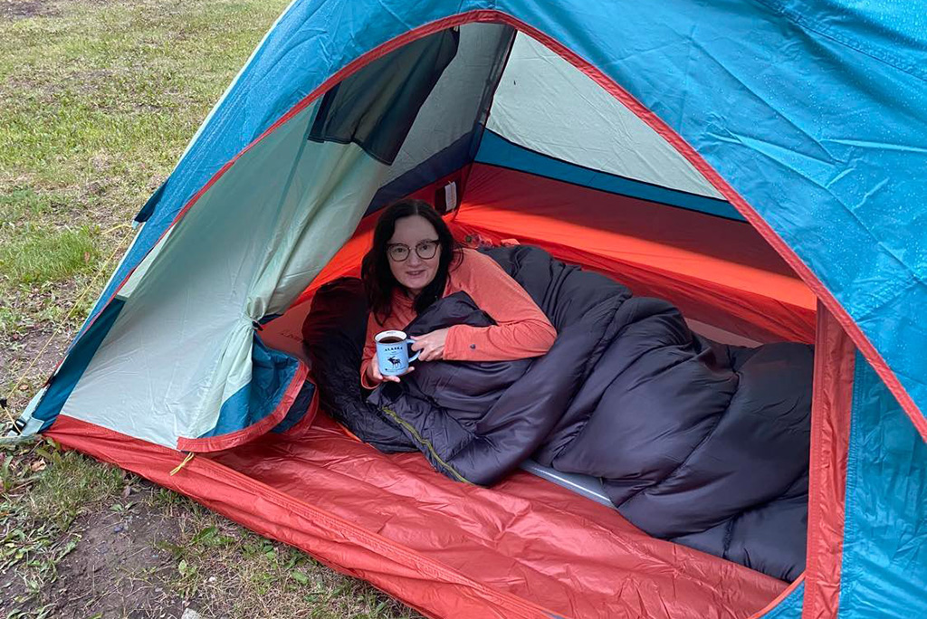 Agnes drinking a coffee in a tent during camping on Dalton Highway.