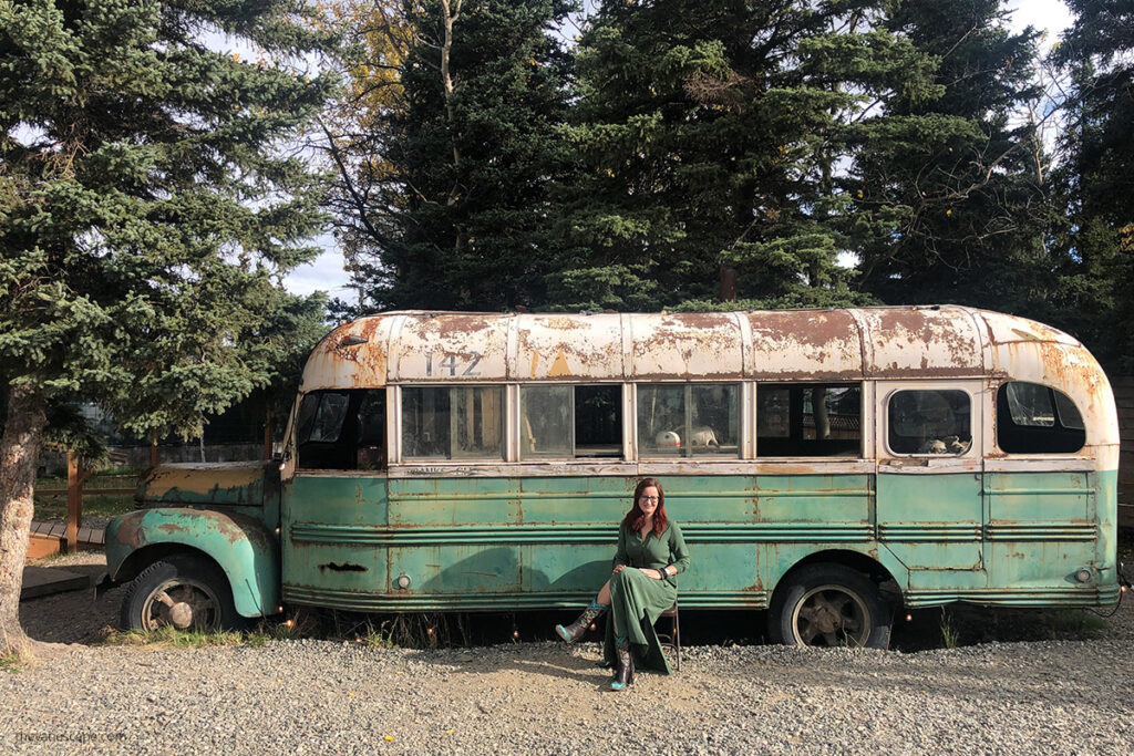 Agnes in green dress at the front of green old bus know as the Magic Bus 142 from the mvie Into the Wild.