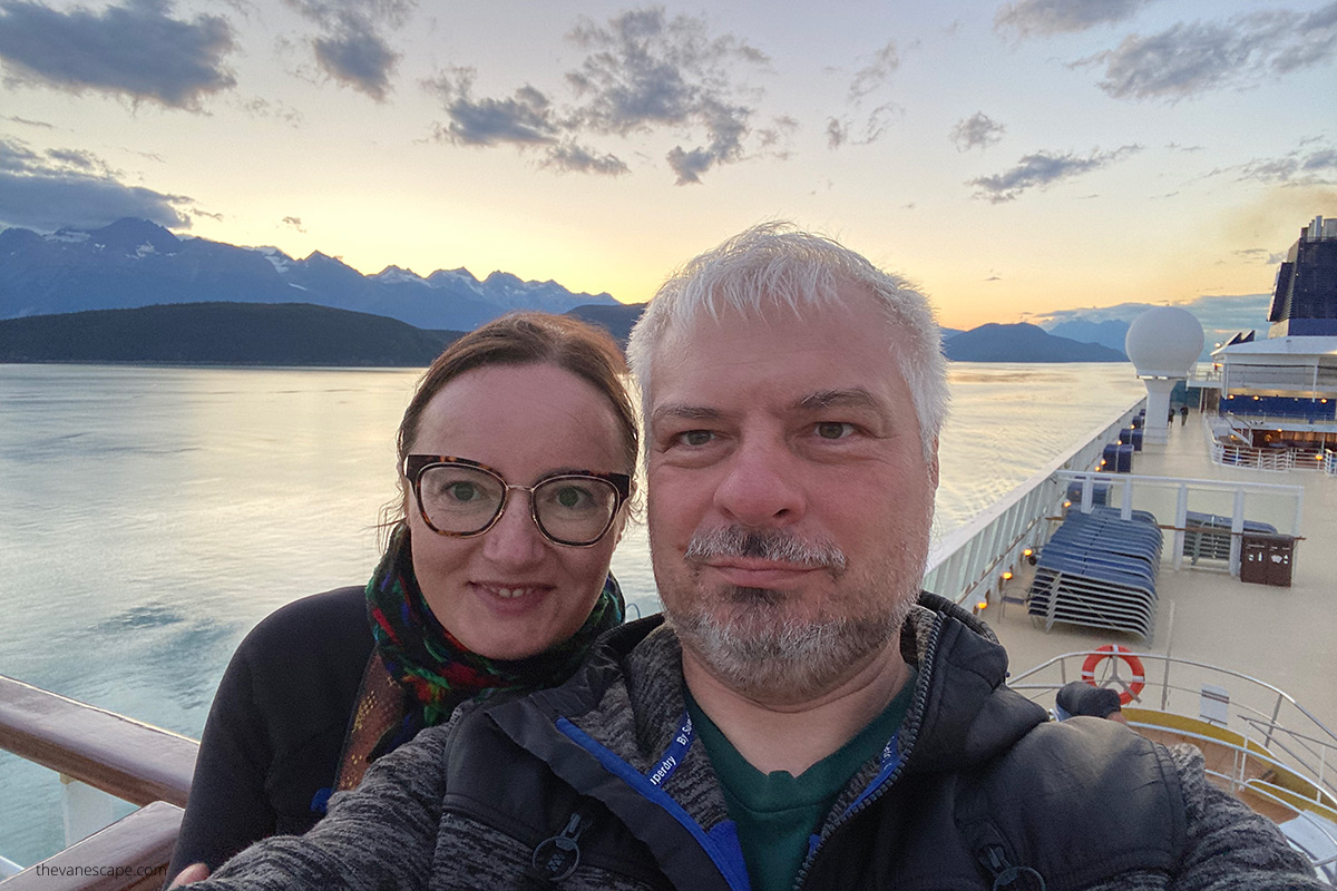 Agnes Stabinska, author, and her partner Chris on Alaska cruise ship during sunset over sea and mountains.