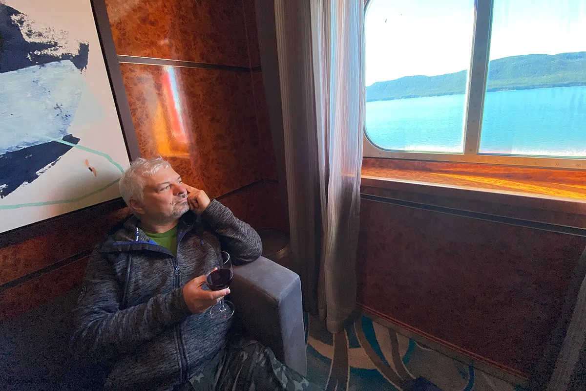 Chris drinking wine with the sea view on cruise ship, as our Alaska cruise price included Unlimited Beverage Package.