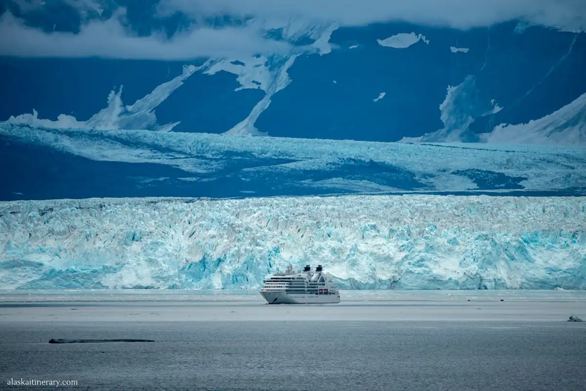 Hubbard Glacier in Alaska with a cruise ship in front of a huge white iceberg.