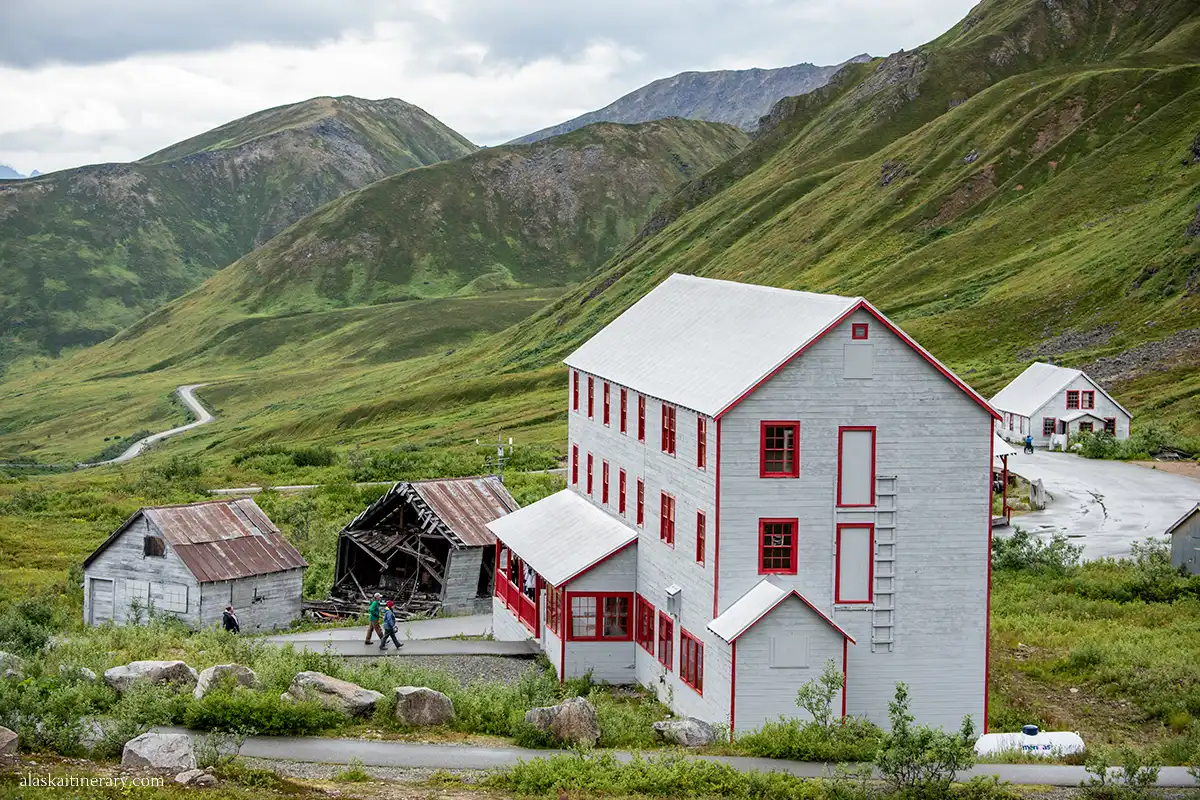 Independence Mine and surrounding buildings at Hatcher Pass, Alaska, set against the lush green of a mountain valley.