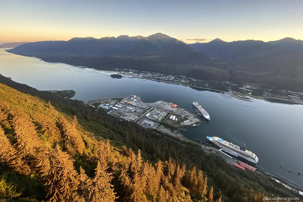 Sunest view during cruise to Alaska in September: cruise ships in port of call, mountain backdrop and forest.