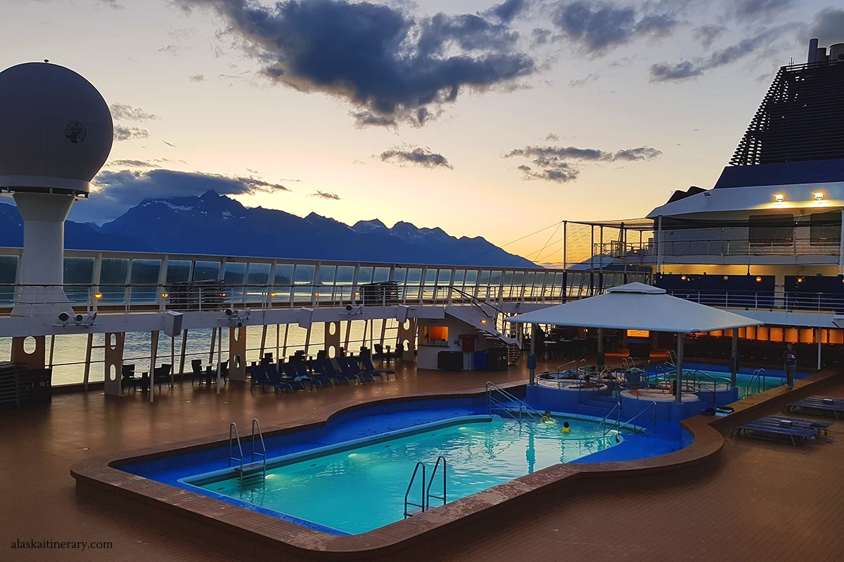Norwegian Sun ship during Alaska cruise with huge swimming pool and mountains in backdrop.