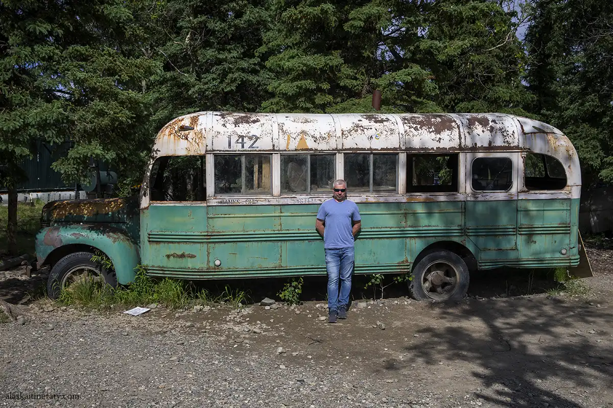 Chris standing at the fron to the replica of Magic Bus 142 from the movie Into the wild.