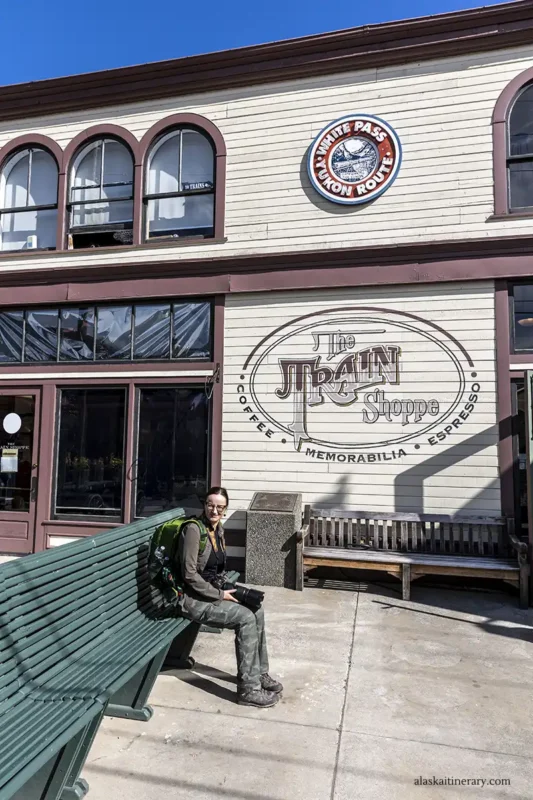 Agnes sitting on bench at the front of the Train shoppe on Skagway depot.