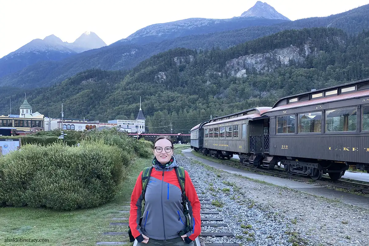 Agnes during shore excursions in Skagway with the old train and mountains in backdrop.