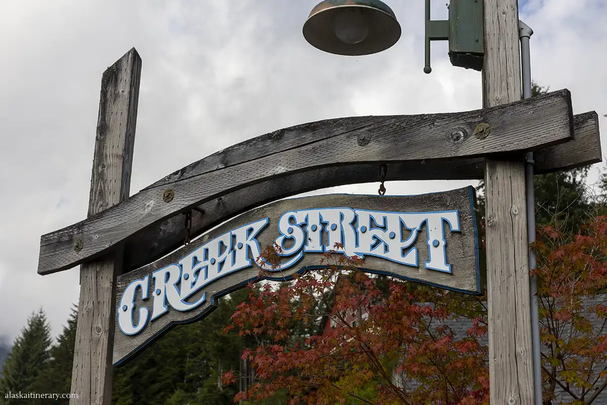 Wooden sign with the words Creek Street in the background with autumn leaves in red and orange shades.