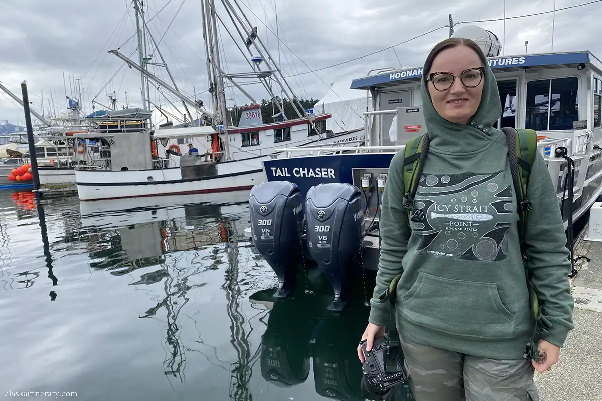 Agnes, the author, with her camera in hand is next to the boat before whale watching tour in Icy Strait Point.