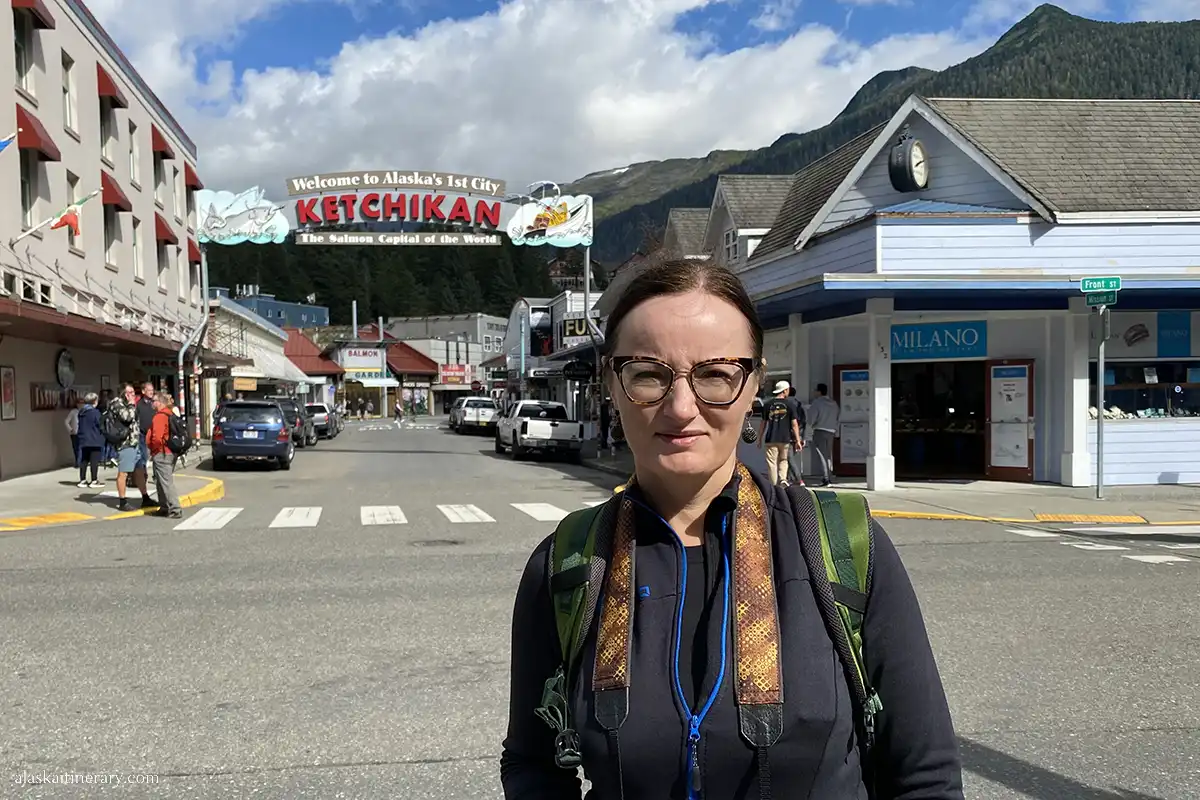 Agnes in front of the Welcome Arch sign in Ketchikan.