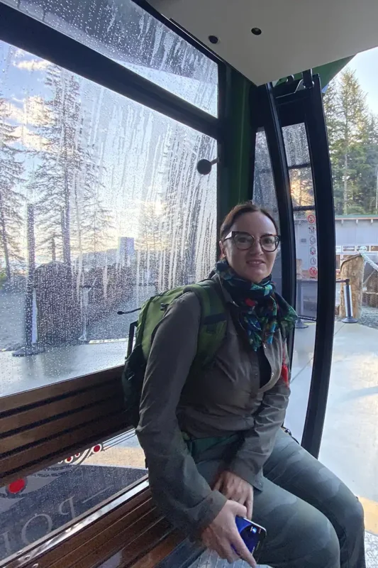 Agnes Stabinska, author, sits in a green gondola car that you can ride for free at Icy Strait Point.