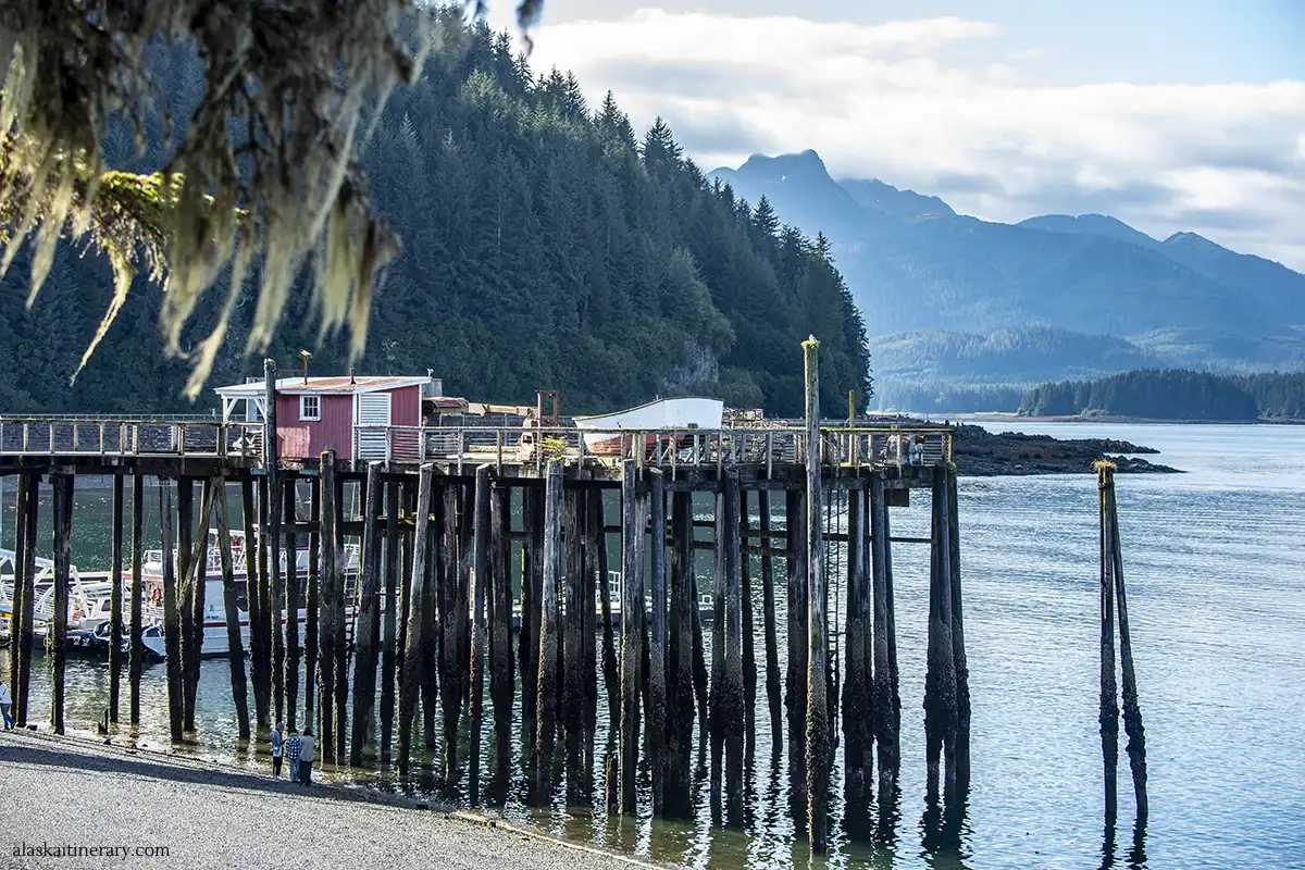 Beach and wooden pier on high wooden stilts at Icy Strait Point with a beautiful mountain view in the background.