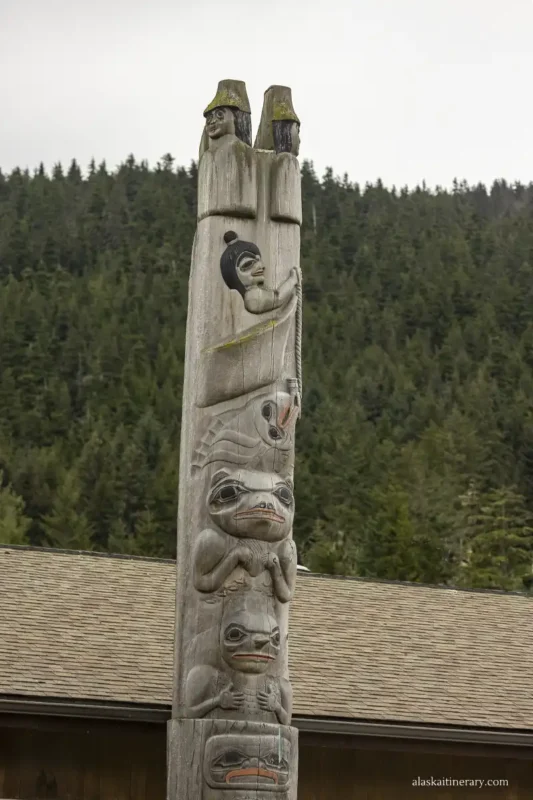 A colorful totem pole in Hoonah with carved animal and human faces.