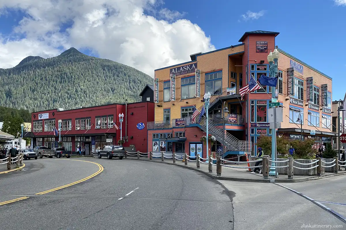 Beautiful historic wooden buildings in downtown Ketchikan in pastel colors, with mountains and trees in the background.