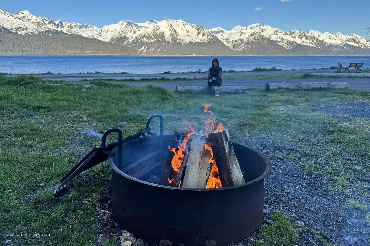 Agnes on a campground next to campfire with mountain backdrop.