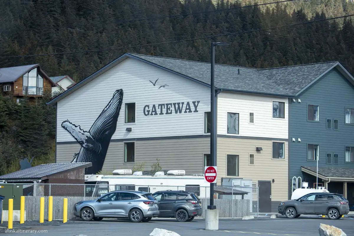Gateway Hotel in Seward with a huge mural of a humpback whale on its wall and parking at the front.