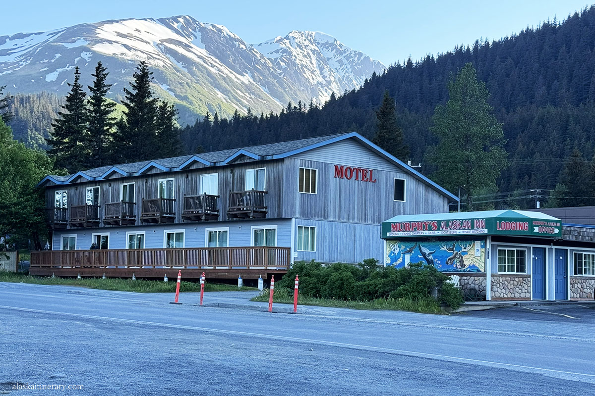 Buildling and entrance to the Murphys Alaskan Inn Motel in Seward with stunning backdrop of mountains and trees.