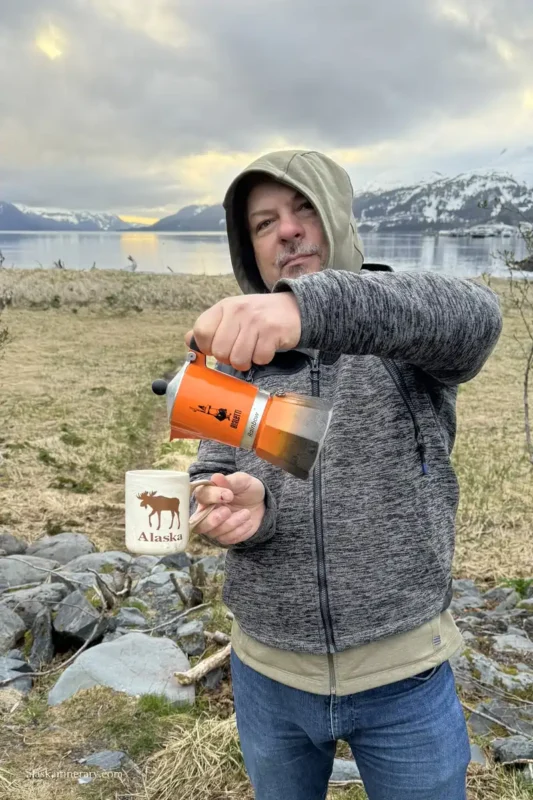 Chris preparing coffee at whittier camping with the bay and mountains view.
