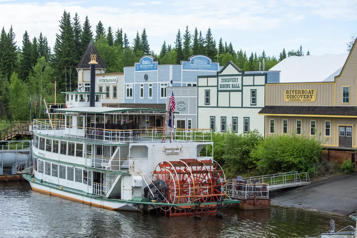 Riverboat Discovery in Fairbanks on Chena River with historic buildlings in the bacdrop.