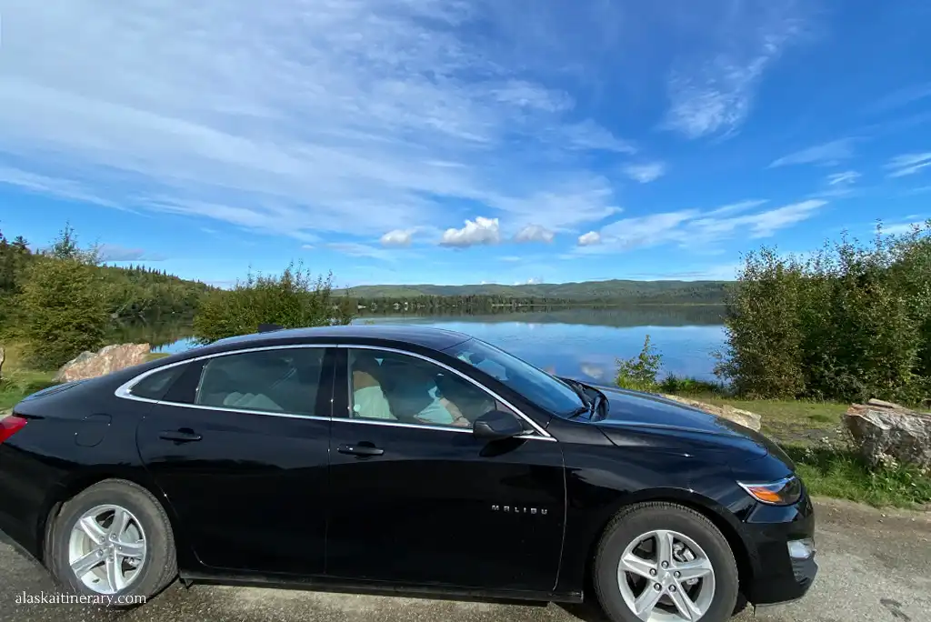 Chris in black rented malibu for alaska road trip.