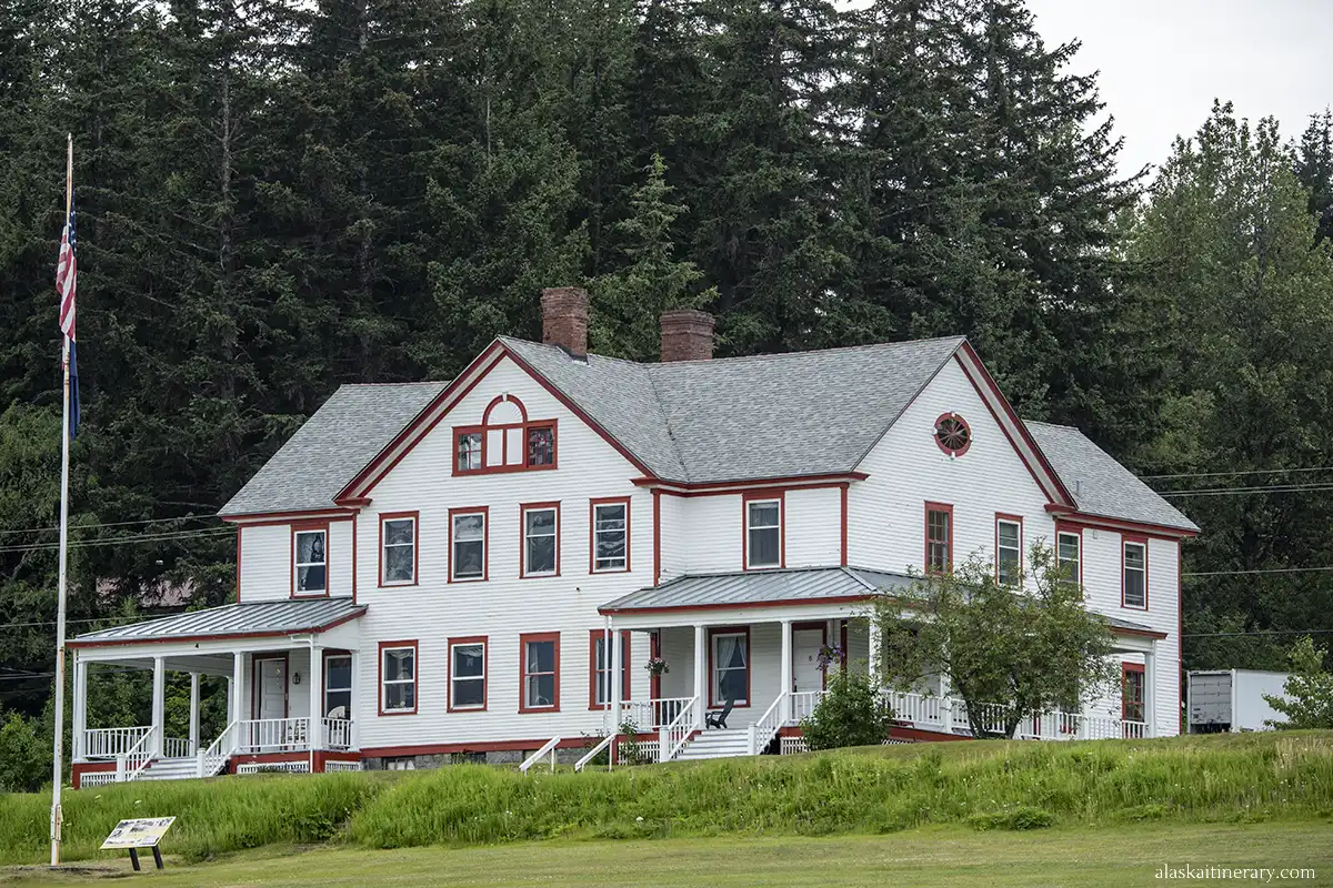 White building with red window trim and doors in Fort William H. Seward.