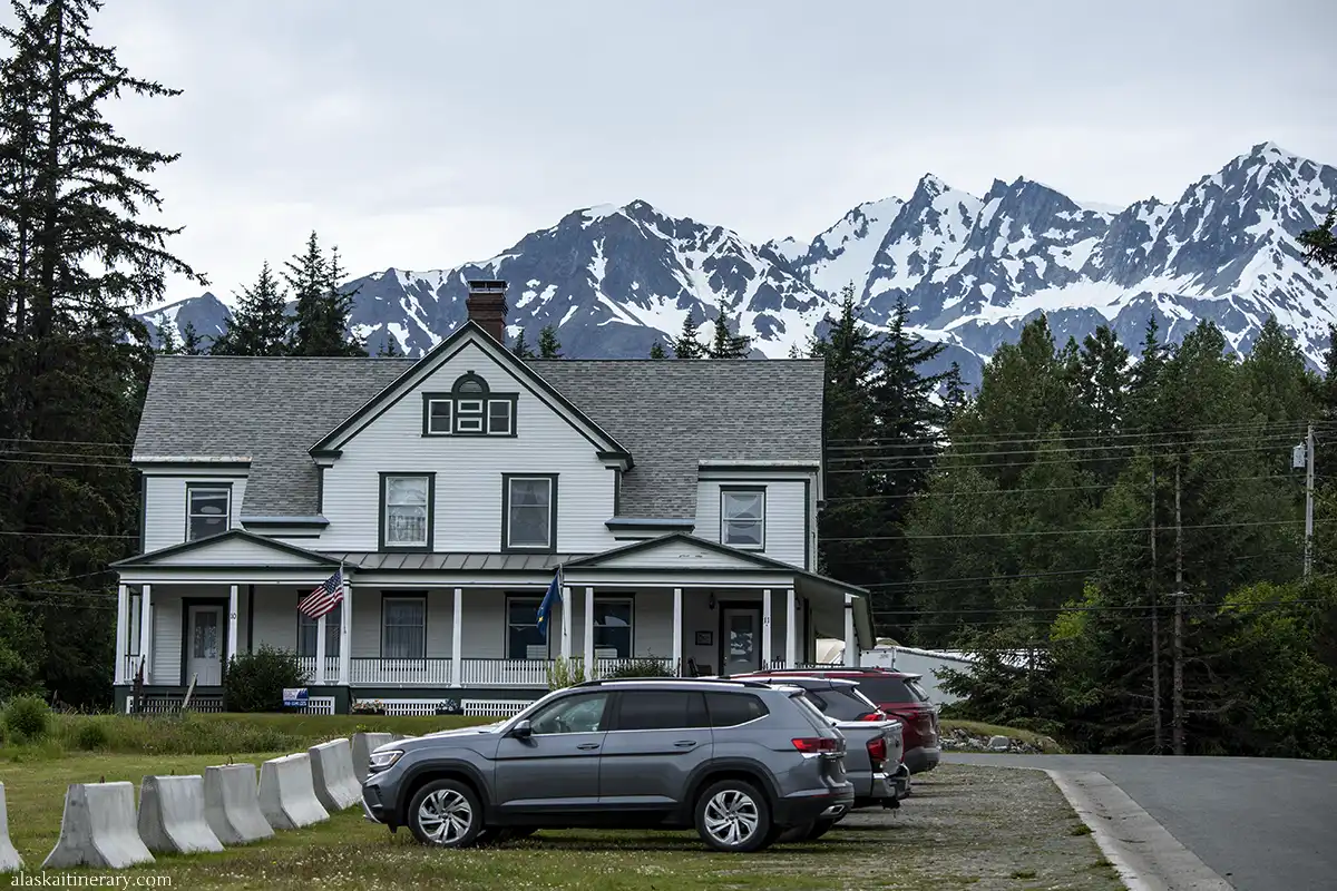 White building with green window trim and doors in Fort William H. Seward and stunning mountain backdrop.