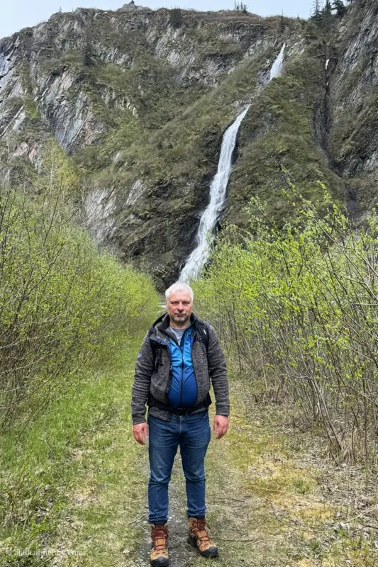 Chris is hiking in Keystone Canyon with a waterfall in the backdrop.