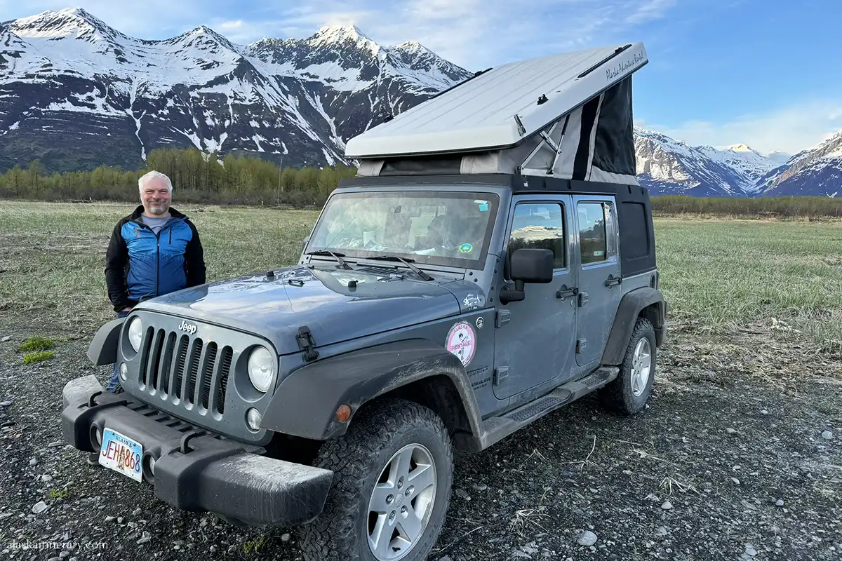 Chris next to jeep wrnagler with a rooftop tent in Valdez, Alaska.