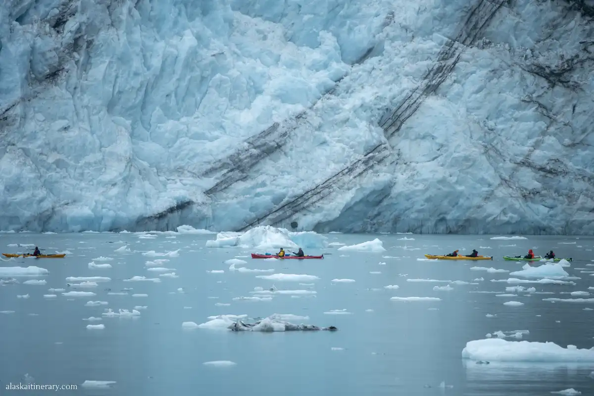 Kayakers next to huge glacier.