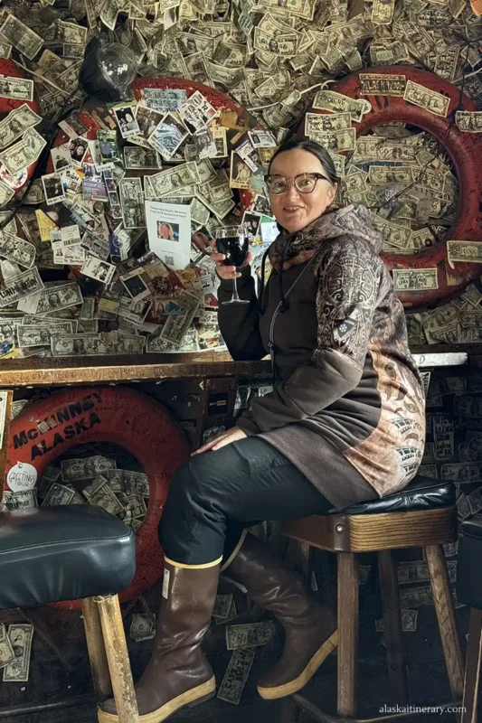 Agnes Stabinska, the author, drinking wine at Salty Dawg Saloon pub with dollars on its walls.