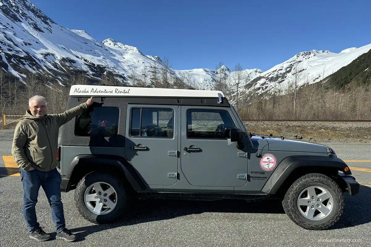 Chris next to Jeep Wrangler with a thumbs up, which shows that the car and rental is great.