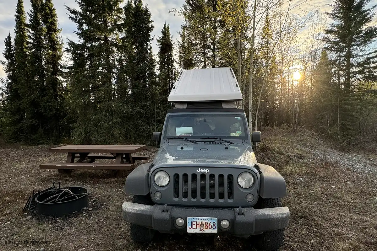 Our rented jepp wrangler with a roof top tent: camping on Nabesna Road next to picnic table and fire ring.