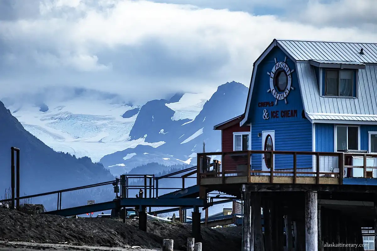 Wooden buildlings at Homer Spit with glaciers and mountains in the backdrop.