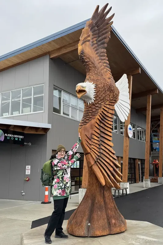 Agnes Stabinska, the author, next to the huge wooden bald eagle statue in Sitka Sound Cruise Terminal.