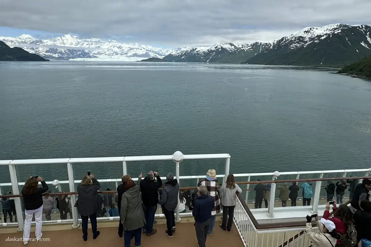Crowd of people on Alaska cruise ship observing glacier from a distance.