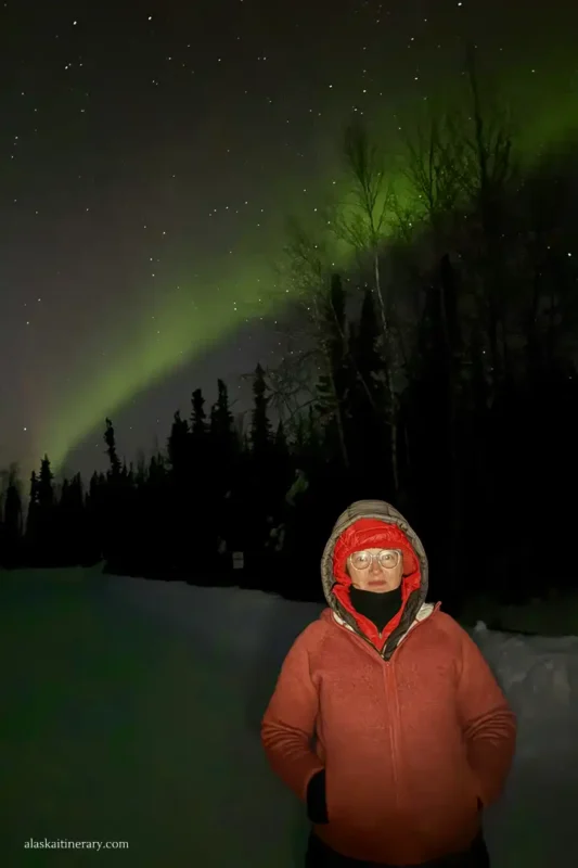 Agnes Stabinska, the author, with northern lights above her head in Fairbanks in winter.