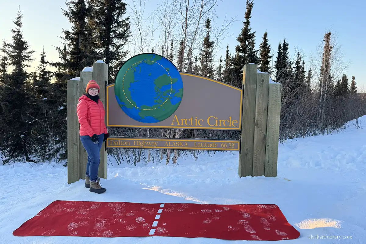 Agnes Stabinska next to the Arctic Circle sign in winter.